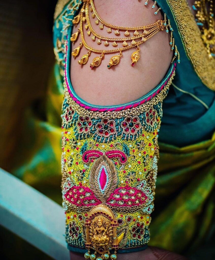 A close-up of a richly embellished traditional garment sleeve with intricate embroidery and jewelry.